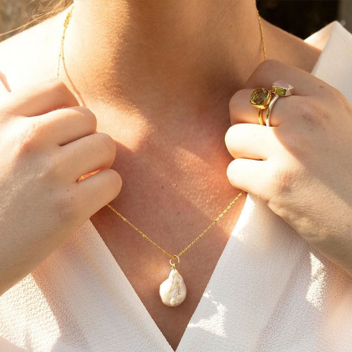 woman wearing ivory baroque pearl necklace with a gold chain.