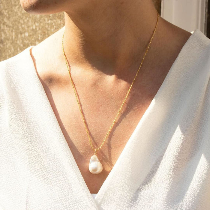 woman wearing ivory baroque pearl necklace on a gold chain.