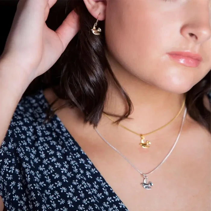 Gold bird charm earrings and layered necklaces in gold and silver, delicate everyday jewellery styling