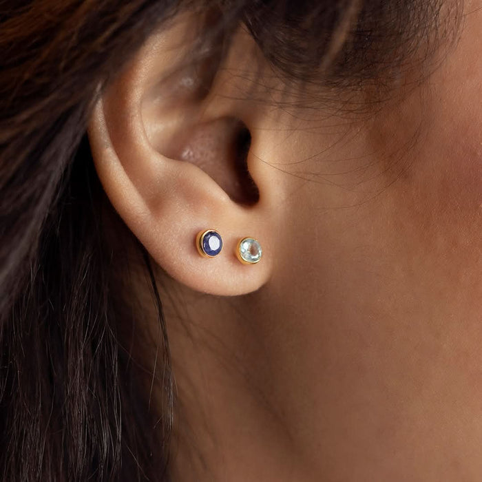 close up of model wearing blue topaz earrings in gold