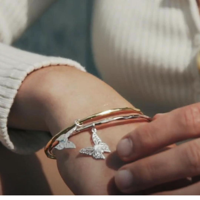 close up of model wearing two butterfly bangles