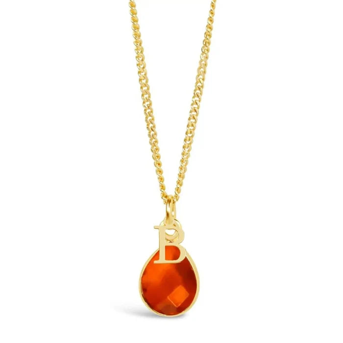 Carnelian teardrop gemstone in a gold setting on a gold curb chain. The necklace has a gold "B" initial ontop of the gemstone and is against a white background