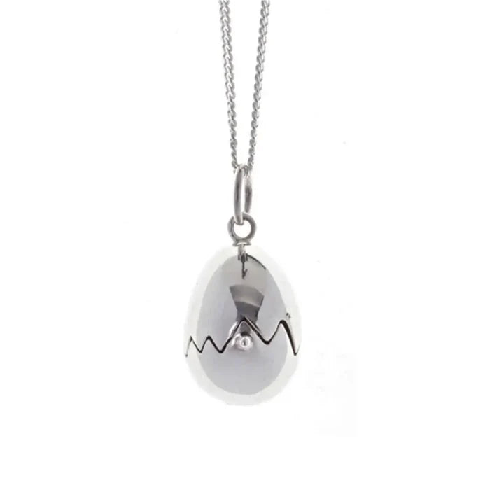 Close-up of sterling silver egg locket pendant with jagged crack detail, high-polish finish and minimalist chain