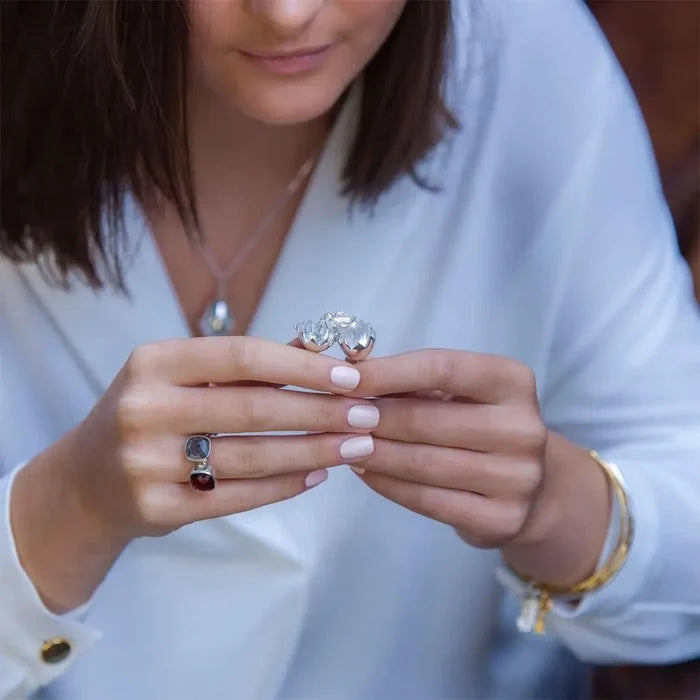 Close-up of model holding silver chick locket necklace, showing scale and polished egg pendant design