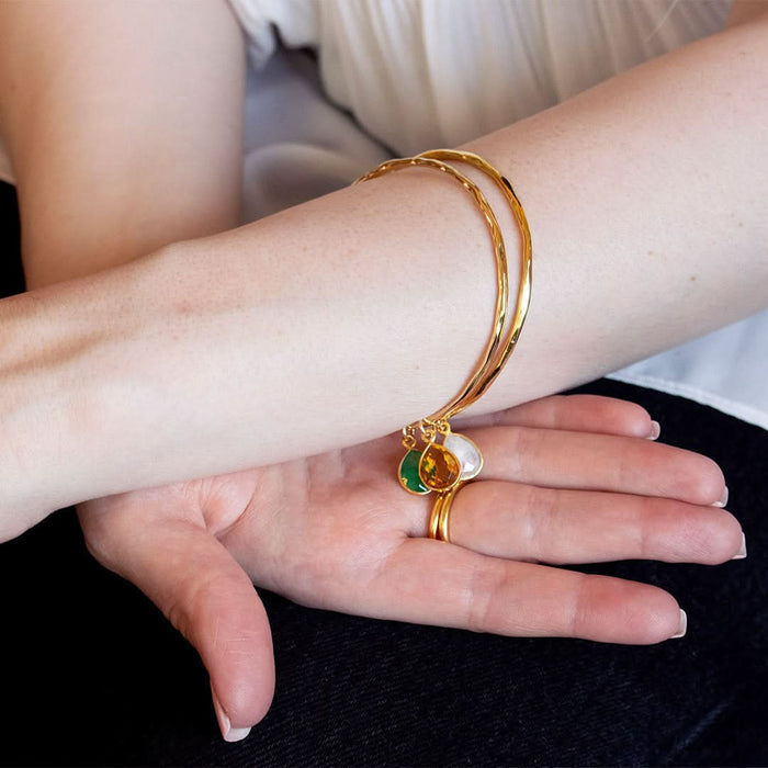 Model wearing thin bangles with tear drop chrysoprase gemstones