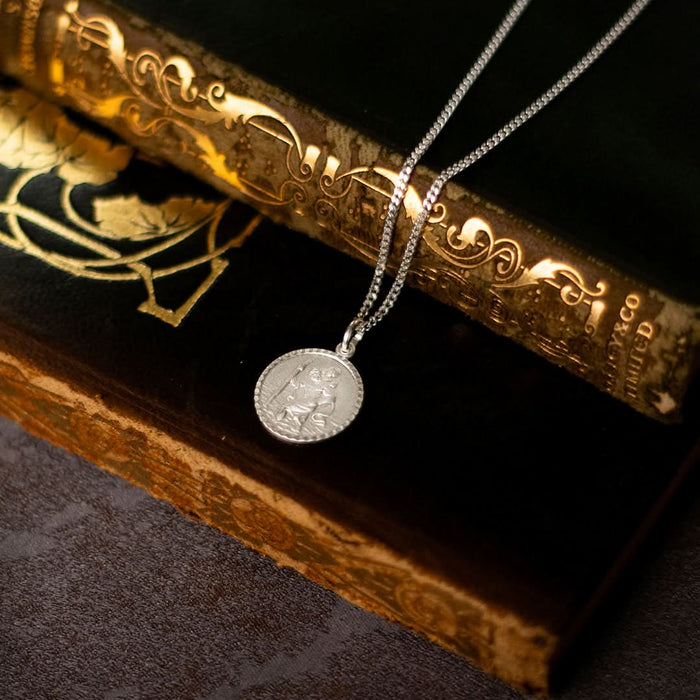 Dainty round sterling silver St Christopher necklace on a chain styled on books