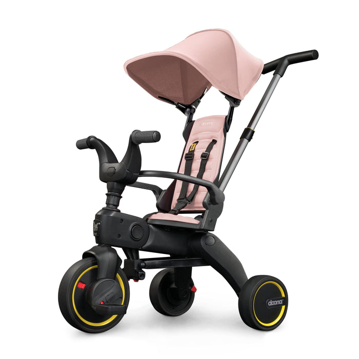 A blush pink Liki Trike S1 with a parent control bar and high & low backrest, designed for toddlers.