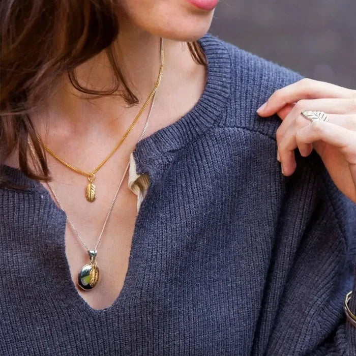 Sterling silver feather locket necklace worn by model, elegant personalised jewellery with symbolic feather charm