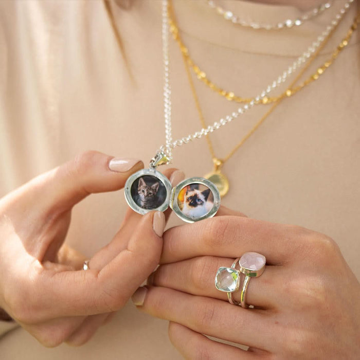closeup of model wearing opened feather locket in white goldwith photos inside
