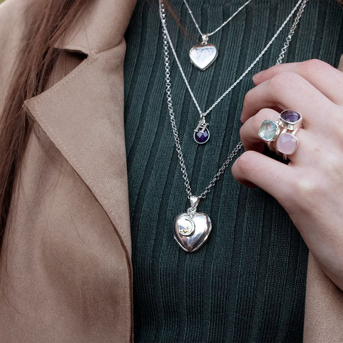 close up of model wearing four photo heart locket in silver with charm attached