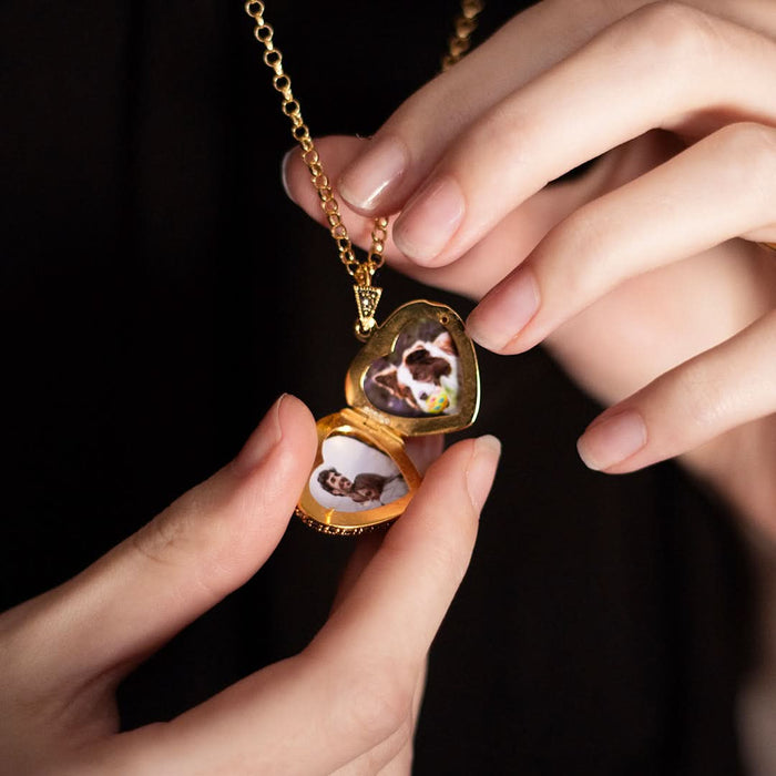 Open vintage gold heart locket necklace with pet photos inside, held in hands