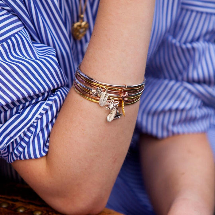 close up of model wearing multiple bangles with charms attached