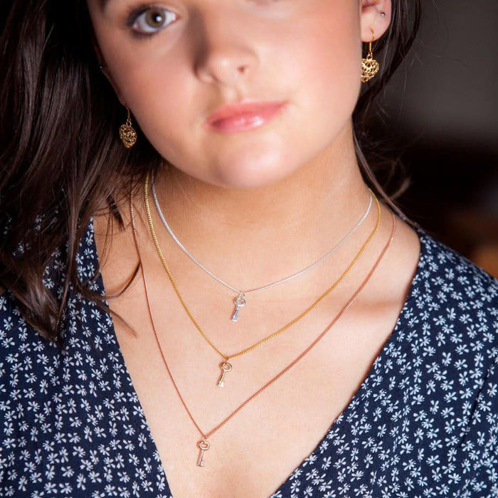 close up of model wearing three key pendants