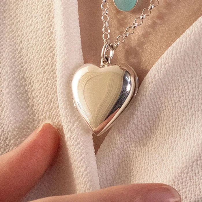 close up image of large 2 photo heart locket in silver being worn by woman
