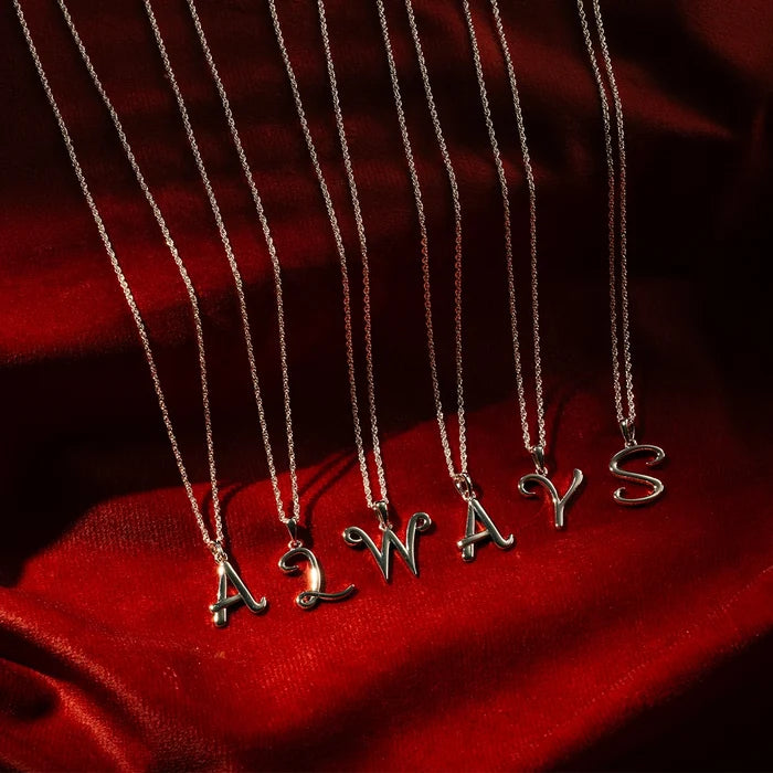 Sterling silver initial necklaces spelling ALWAYS on fine chains, styled on red satin background
