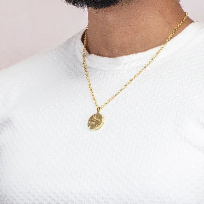 Gold compass locket necklace worn on chain over white shirt, minimal everyday styling