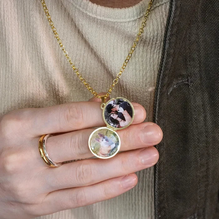 Close-up of a person holding an open gold St Christopher locket displaying two personalised photos inside