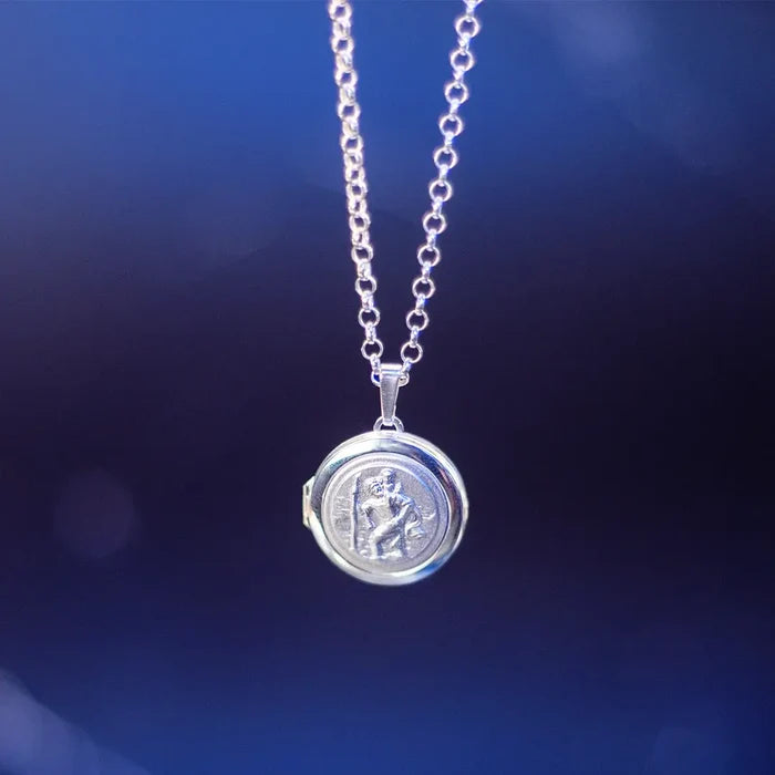 Sterling silver St Christopher locket necklace on a chain against a dark blue softly lit background