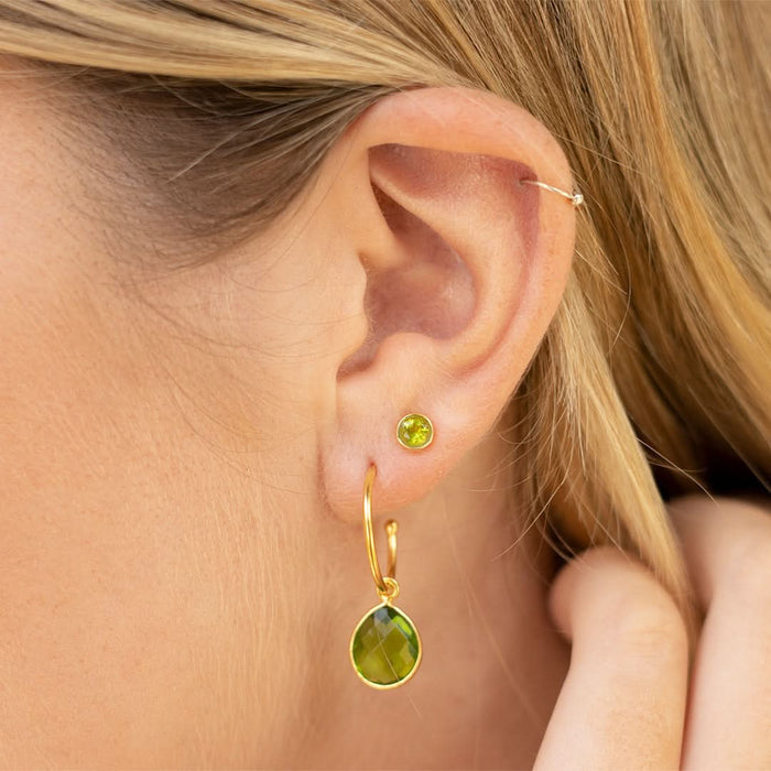 close up of model wearing peridot hoop earrings and stud earrings in gold