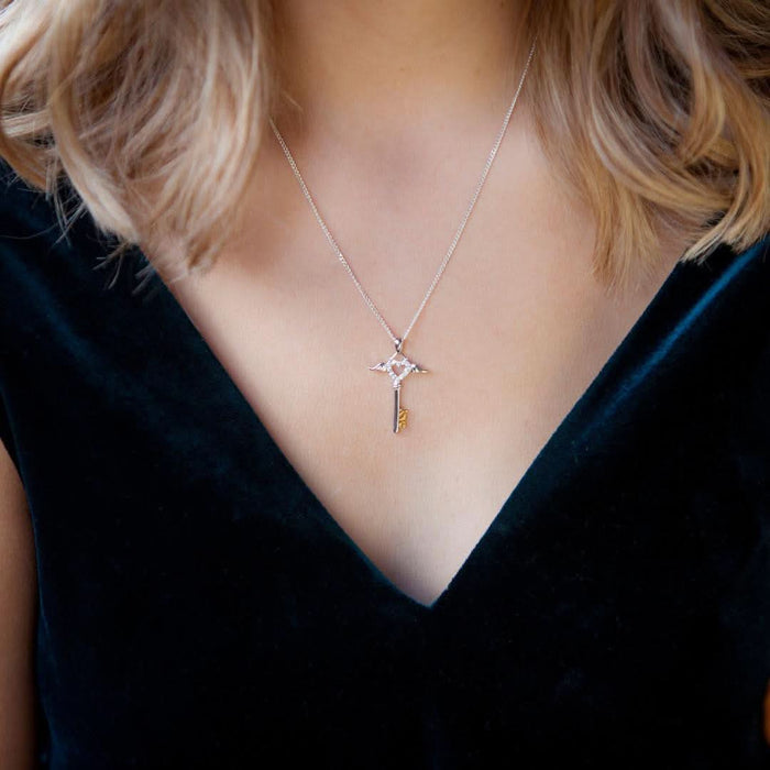 Model wearing Angel wing key pendant in silver and gold on a silver curb chain