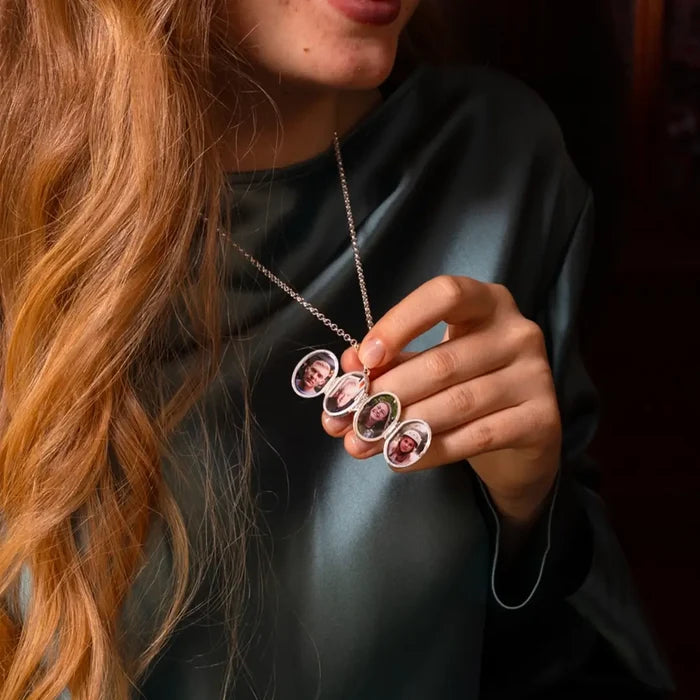 Sterling silver expanding oval locket held open by model, displaying multiple personalised family photographs inside individual oval frames.