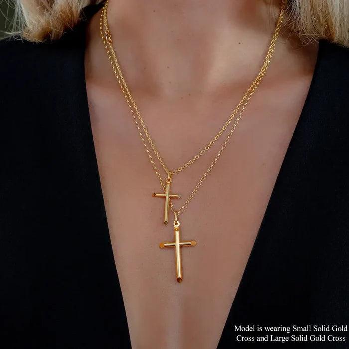 Model wearing layered solid  9ct gold cross pendant necklaces featuring small and large polished cross designs on fine chains, styled with black outfit