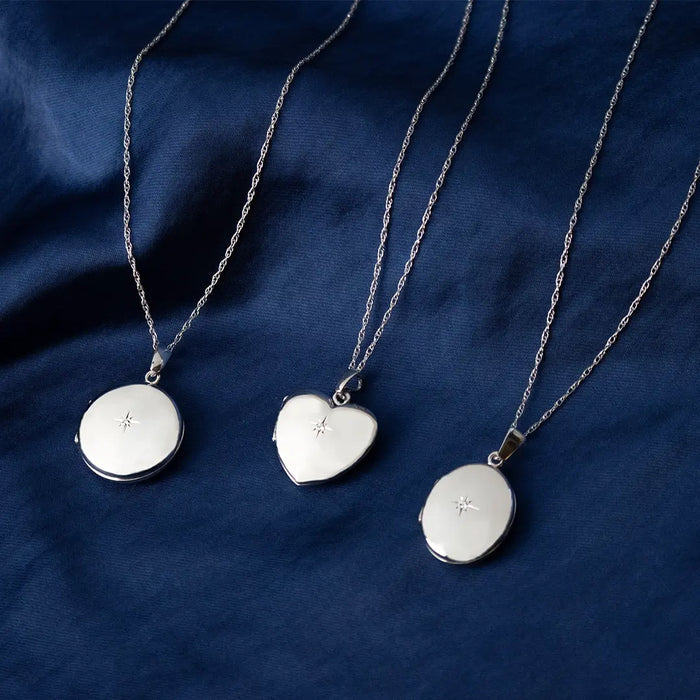 Solid White Gold round, heart and oval lockets with star detail on fine chains, displayed on navy fabric background